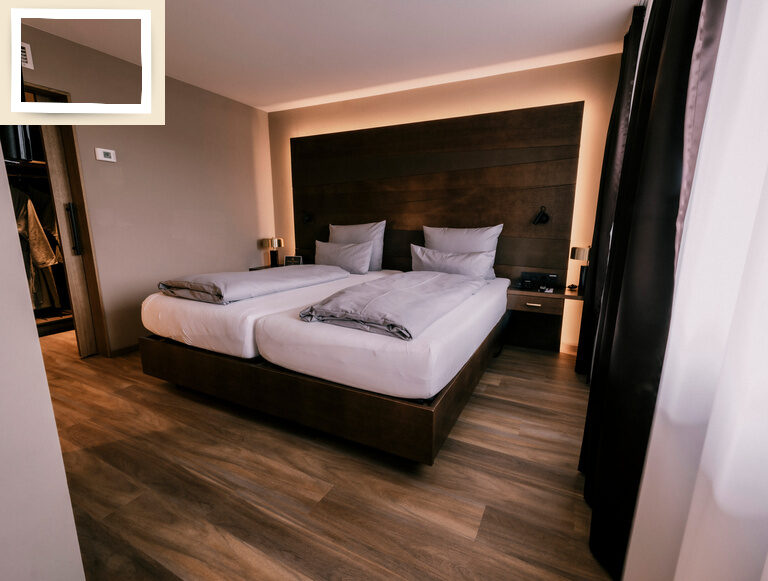 Geräumige Suite Goldrenette im Thermenhotel Holzapfel in Bayern mit einem komfortablen Bett auf Holzparkett.
