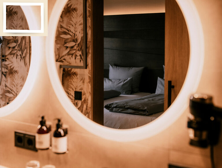 Stilvolles Badezimmer in der Suite Goldrenette mit zwei runden Spiegeln an der Wand des Bades im Thermenhotel Holzapfel in Bayern.