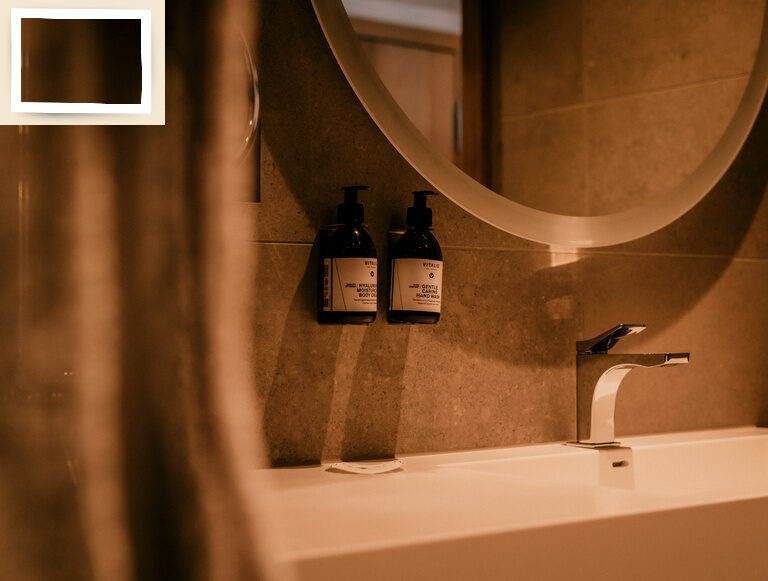 Ein modernes Waschbecken mit eleganter Armatur und Seifenspendern im hellen Badezimmer Einzelzimmer Comfort des Thermenhotels Holzapfel im Rottal.
